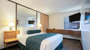 A hotel room with a bed, bedside lamps, a TV, a window, and a wooden nightstand. - Limited Time: 50% Off New Year's Week at Incline Village Club Tahoe (iNCLINE vILLAGE)