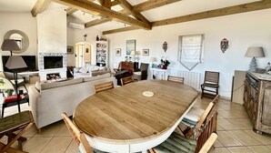 Uma sala ampla com uma grande mesa de jantar de madeira, lareira e um aconchegante espaço de estar.