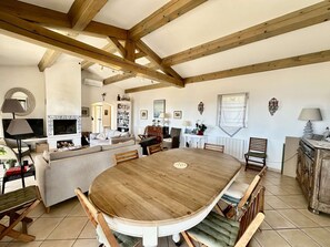 Ein geräumiger Wohnbereich mit einem großen Holzesstisch, einem Kamin und einer gemütlichen Sitzecke.