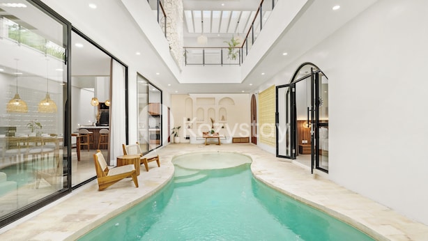 A modern indoor pool area with a glass wall, wooden lounge chairs, and a ceiling with recessed lighting. - Sadin Villa by Kozystay - Sanur (Kerobokan)