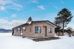 Moderni talo, jossa on puinen julkisivu, suuret ikkunat ja ovi.