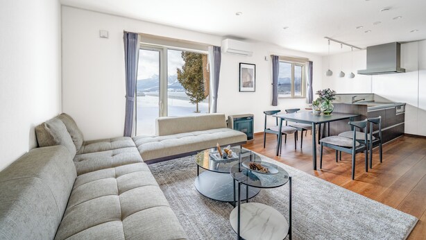 Ein modernes Wohnzimmer mit einer Couch, einem Glastisch und einem Essbereich mit Stühlen.