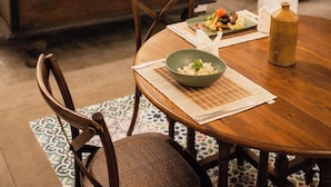A dining area with a wooden table, chairs, and a buffet counter with plates on the wall. - Villa Sayura by TONIK, Galle (Boossa)