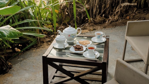 A table set with tea and cookies on a glass table near a beach, surrounded by plants. - Villa Sayura by TONIK, Galle (Boossa)
