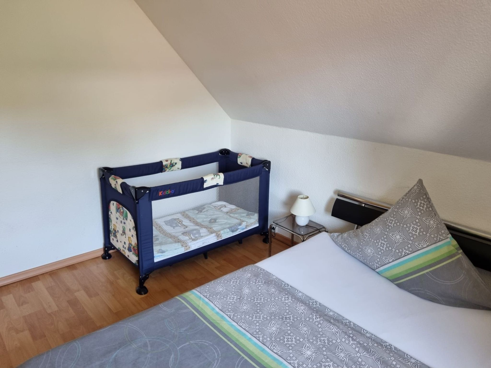 A bedroom with a bunk bed, a bedside table with a lamp, and a patterned pillow.