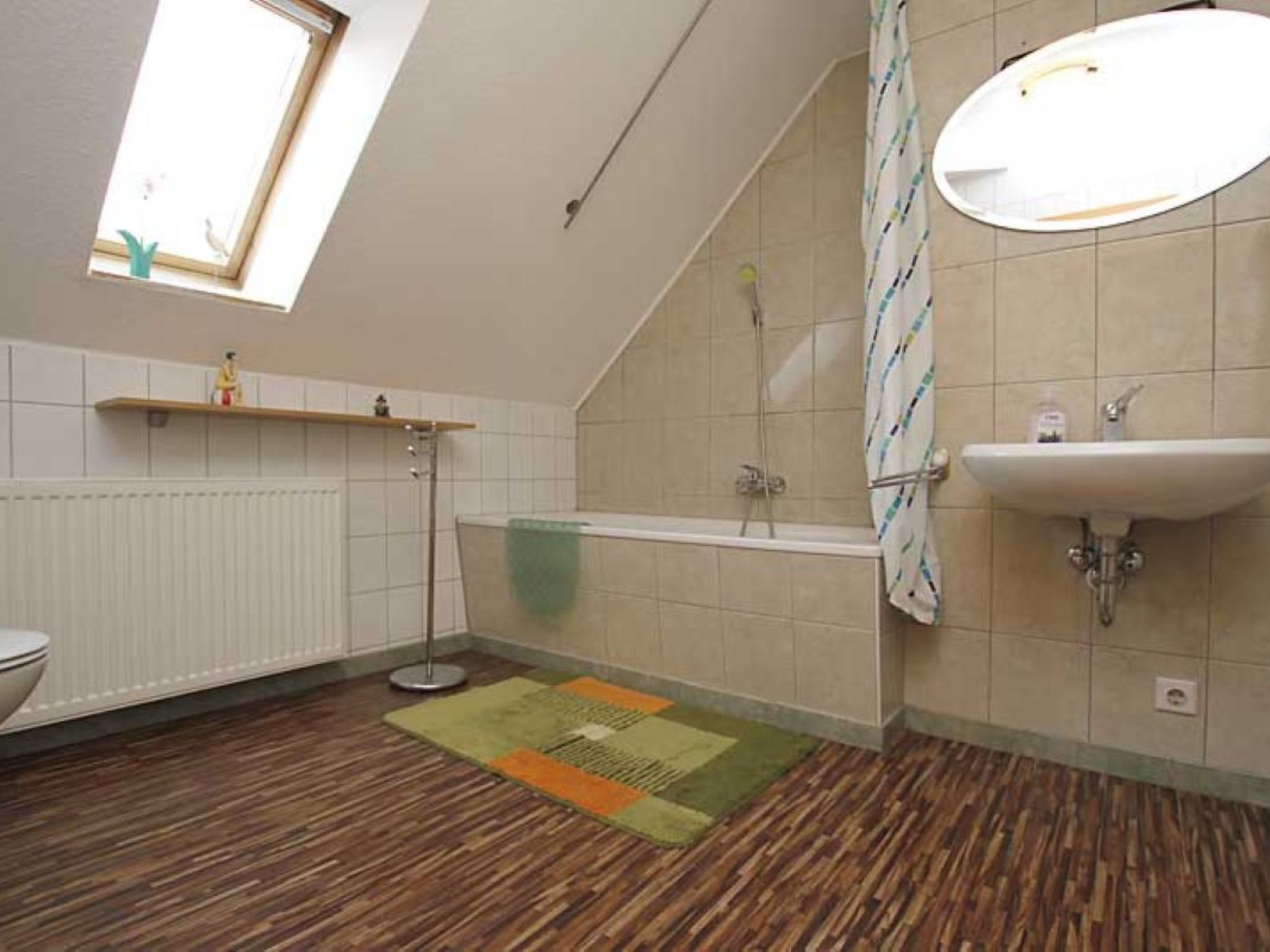 Un baño con tragaluz, bañera, lavabo e inodoro.