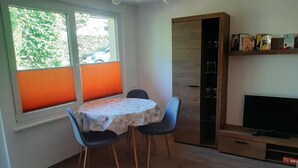 Ein Essbereich mit einem runden Tisch, zwei Stühlen, einem Fernseher und einem Bücherregal.