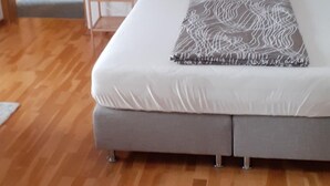 Ein Schlafzimmer mit einem Bett, Kissen, einem Nachttisch und einer Lampe.