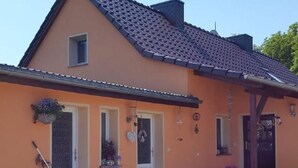 Ein traditionelles Haus mit Ziegeldach, einem gepflasterten Eingang und verschiedenen Topfpflanzen.