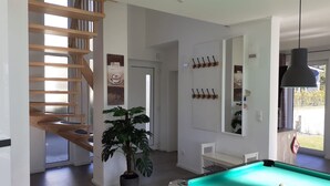 Een moderne woonkamer met een pooltafel, een trap en een grote potplant.