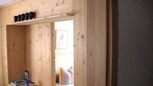 Een houten muur met een plank waarop boeken liggen en een tafeltje met een plant.