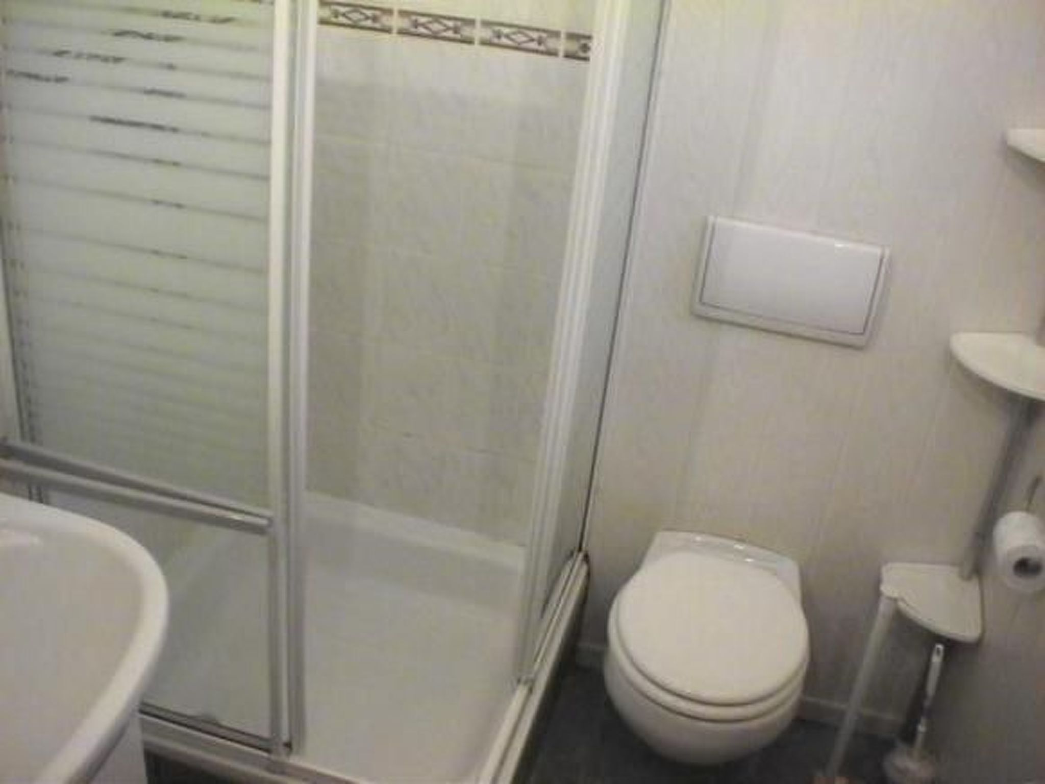 A bathroom with a toilet, a shower enclosure, and a sink.