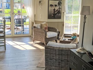 A room with wicker furniture, a sofa, a table with a lamp, and a painting on the wall. - Reetdachhaus am Wasser mit Sauna, Außenwhirlpool by Interhome (Bodstedt)