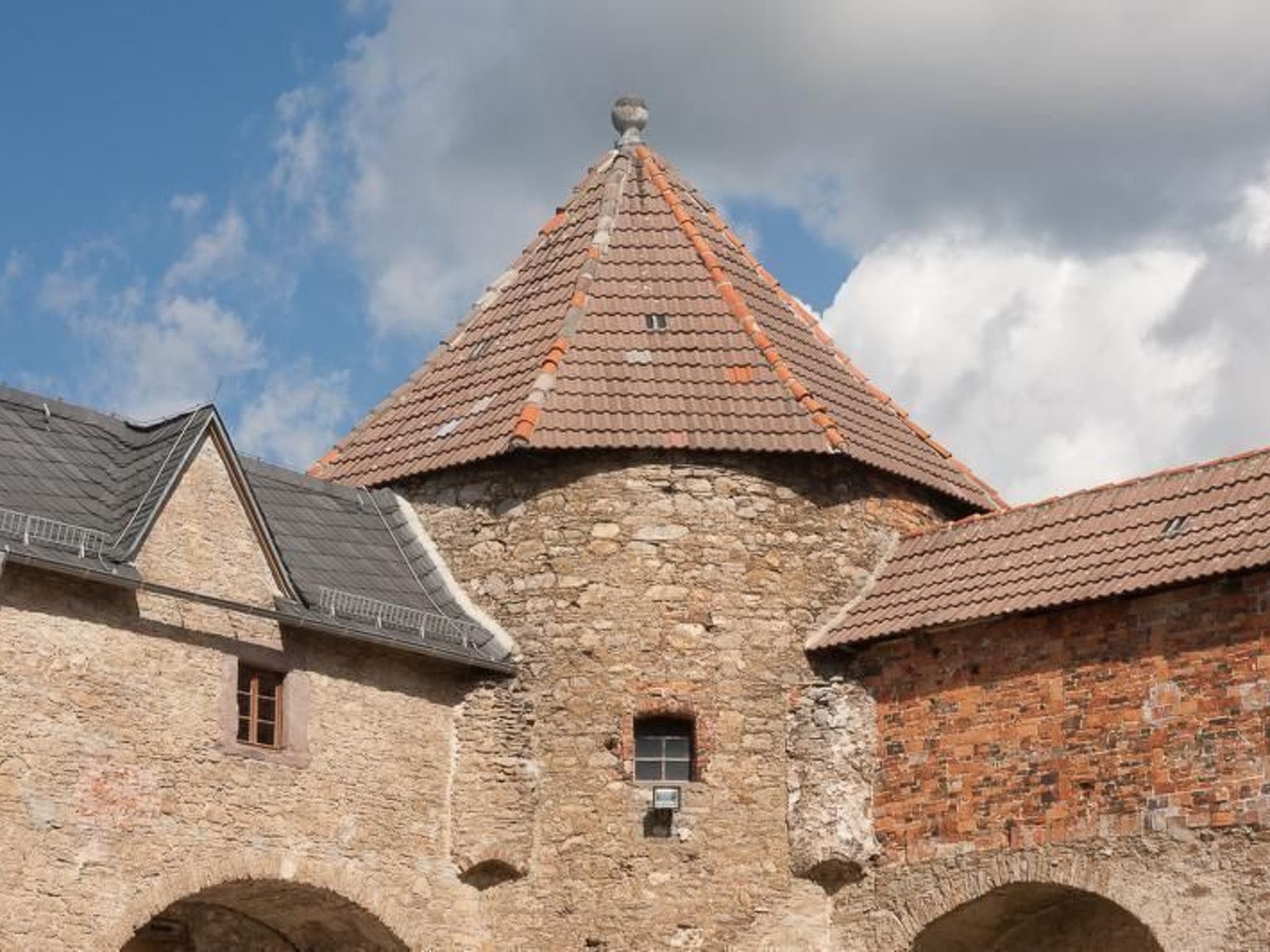 A stone building with a conical roof and arched windows.