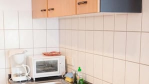 Eine Küche mit Holzschränken, einer Mikrowelle, einer Kaffeemaschine, einem Spülbecken und einem Herd.