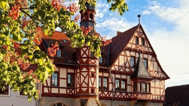 Ein traditionelles Fachwerkhäuschen mit einem markanten Turm und Rundbogenfenstern.