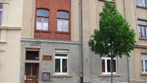 A building with a brick facade, a wooden door, and a sign that reads "Kunst Asyl".