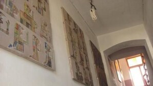 A hallway with a staircase leading to a landing. The walls are adorned with various posters and artwork.