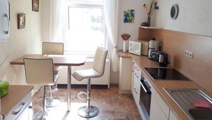 Cocina compacta con comedor, microondas, cafetera y lavabo.