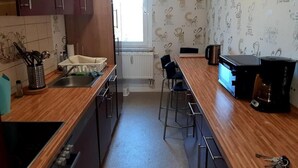 Eine kleine Küche mit Holzarbeitsplatten, einem eingebauten Backofen, einer Kaffeemaschine und einem Fenster mit Tageslicht.