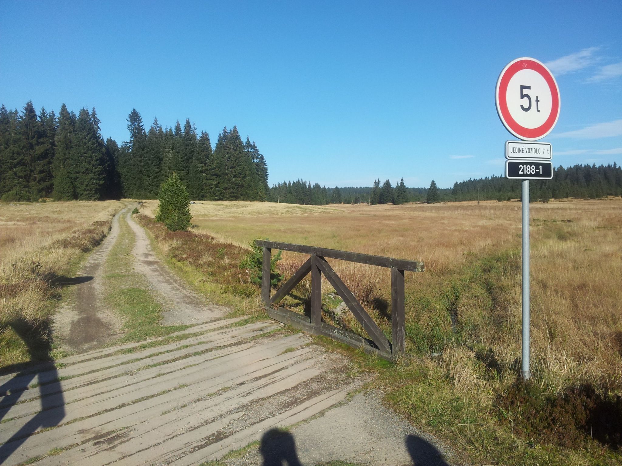 A rural road with a wooden gate and a speed limit sign.