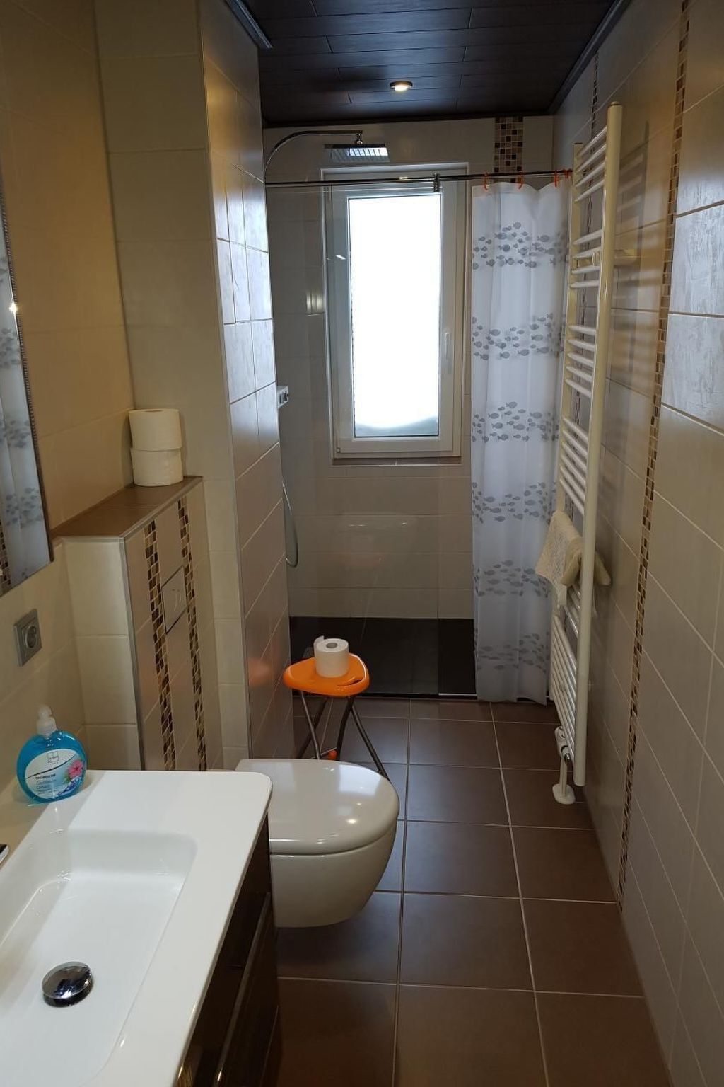 A compact bathroom with a bathtub, toilet, and a small window.