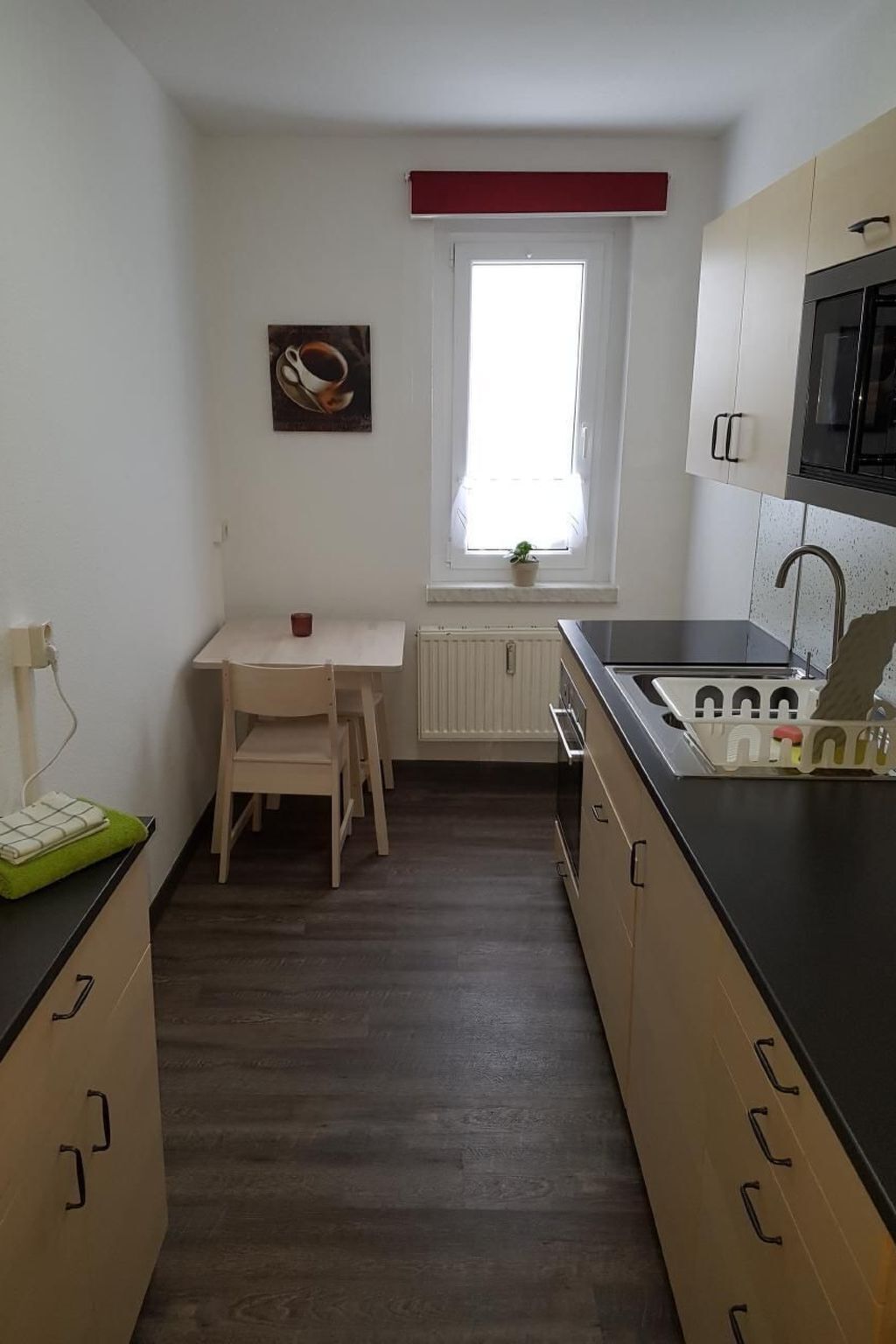 Une cuisine compacte équipée d’une table à manger, d’un four à micro-ondes et d’une fenêtre donnant sur un paysage agréable.