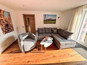 A modern living room with a grey sectional sofa, a grey armchair, and a small white coffee table. - Ferienapartment Horn by Interhome (Altendorf)