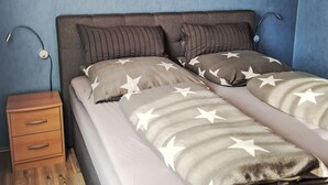 Une chambre à coucher comprenant un lit, deux tables de chevet, une commode et une lampe fixée au mur.