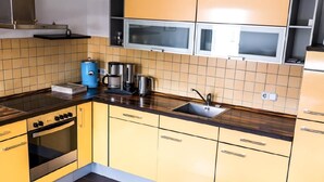A kitchen with yellow cabinets, a stainless steel range hood, a coffee maker, and a sink.