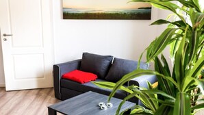 A modern living room with a dark grey sofa, a red cushion, and a small table with two metallic objects.