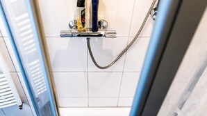 A shower with a handheld showerhead and a handheld soap dispenser.