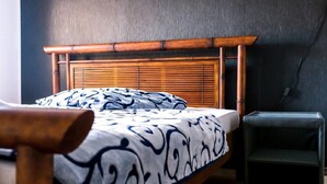 A bed with a wooden headboard, a patterned bedspread, and a small bedside table.