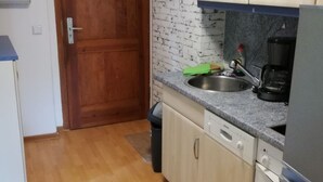 Une cuisine compacte dotée de meubles en bois, d’un plan de travail en granit, d’un évier en acier inoxydable et d’un lave-vaisselle encastré.