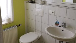 Une petite salle de bain avec des toilettes, un lavabo et un miroir.