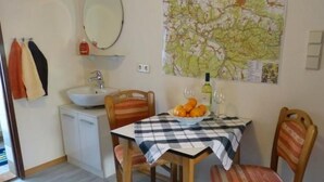 Un comedor con una mesa dispuesta para dos personas, un mapa en la pared y un lavabo con un espejo encima.