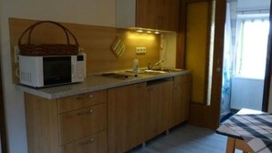 Una cocina compacta con armarios de madera, un microondas y un lavamanos.