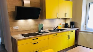 Una cucina compatta con mobili gialli, un piano di lavoro nero e una sedia.