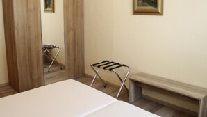Una camera da letto con un letto, un armadio in legno, uno specchio, un quadro appeso e una stendibiancheria in metallo.