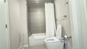 A bathroom with a shower, toilet, and bathtub.