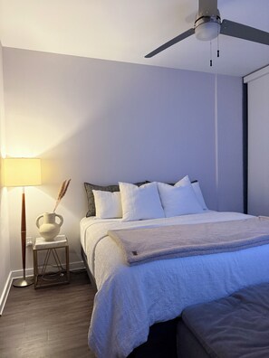A bedroom with a bed, a bedside lamp, and a ceiling fan.