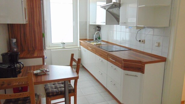 A kitchen with white cabinets, a wooden countertop, a stove, and a window. - Blaues Haus by Interhome (Meißen)