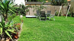 A backyard with a wooden fence, a swing set, and several potted plants. - Blaues Haus by Interhome (Meißen)