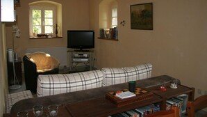 Uma sala de estar aconchegante com um sofá xadrez, uma mesa de centro de madeira e uma televisão.