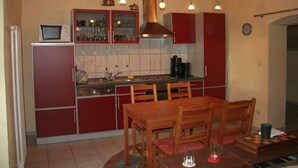 Uma cozinha compacta com armários vermelhos, uma mesa de madeira e um fogão.