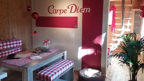 Een gezellige kamer met een geruite bank, een kleine tafel, een rode muur met de tekst 'Carpe Diem' en een potplant.