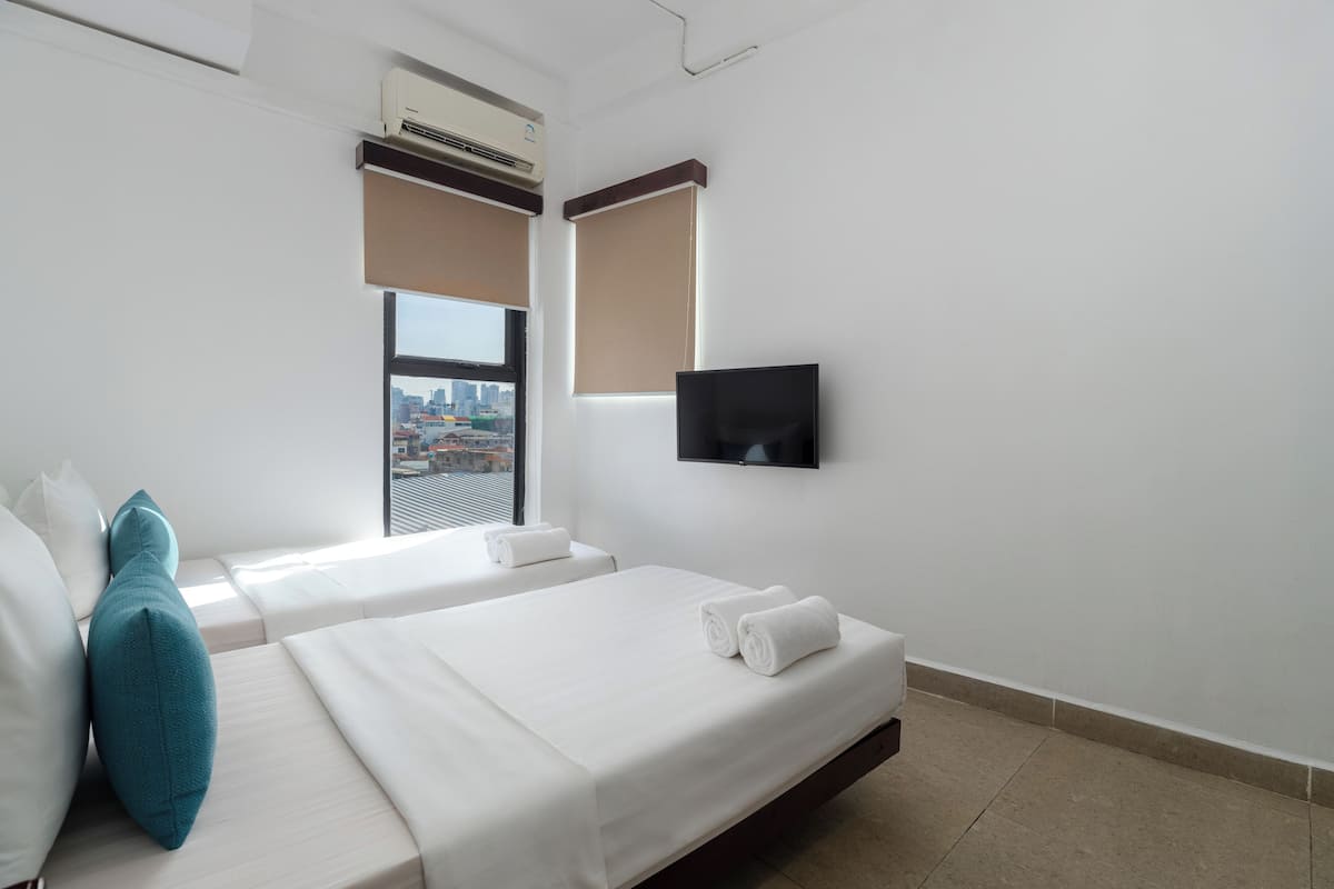 A hotel room with two beds, a TV, and a city view.