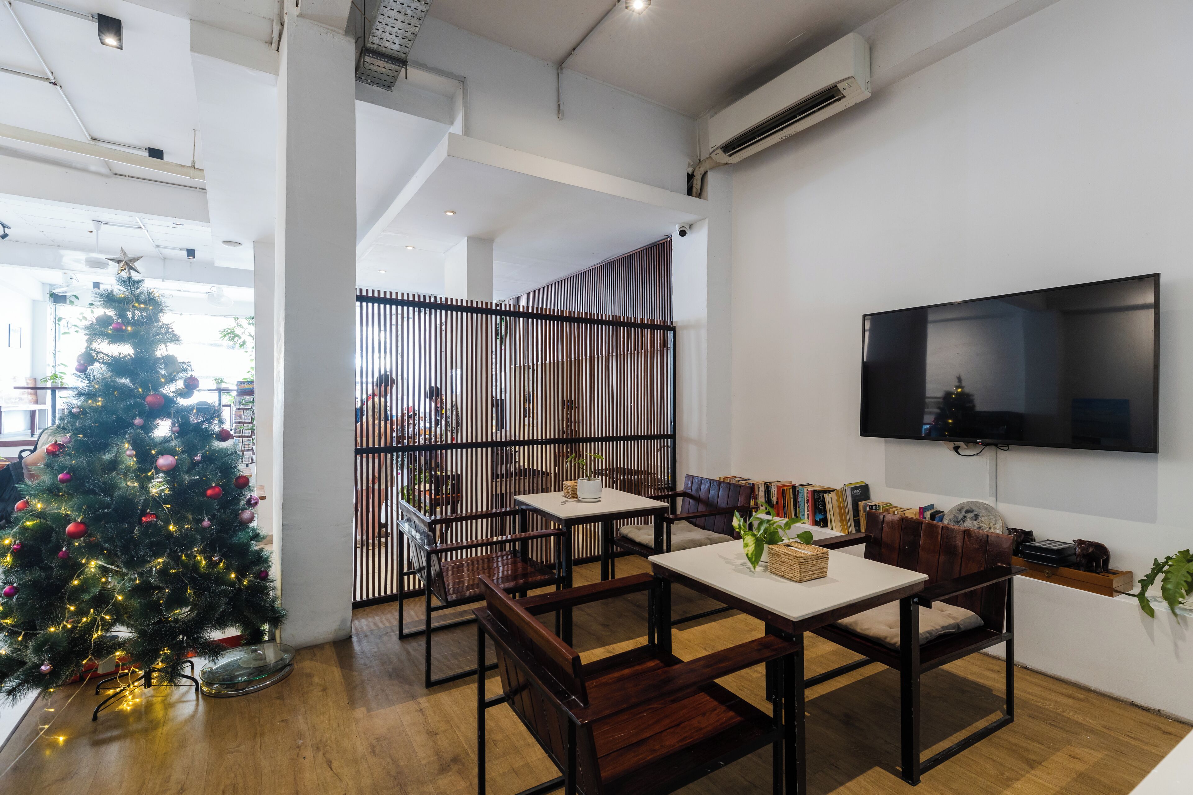A modern interior with a Christmas tree, wooden furniture, and a flat-screen TV.