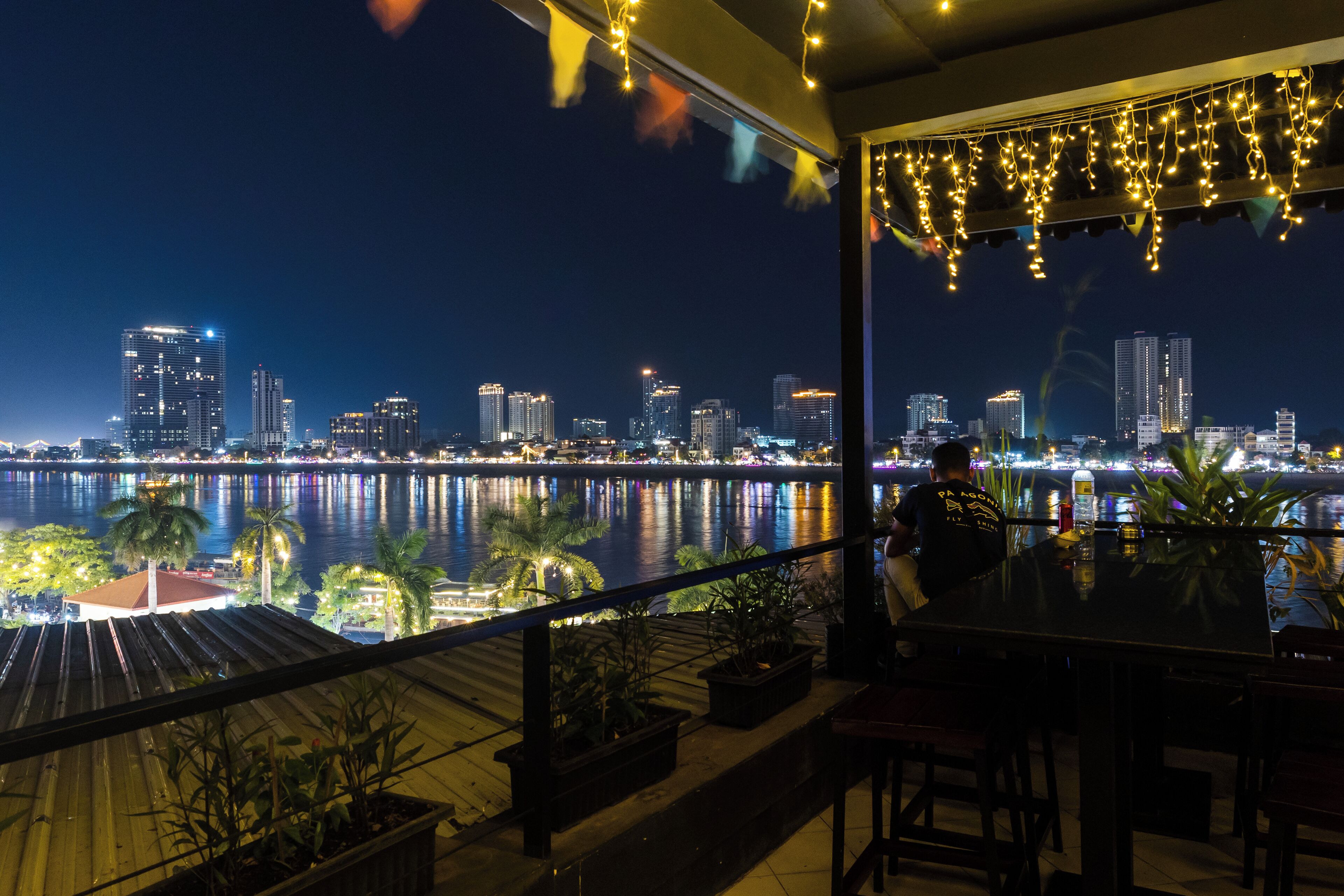 A balcony with a view of a city skyline and a body of water at night.