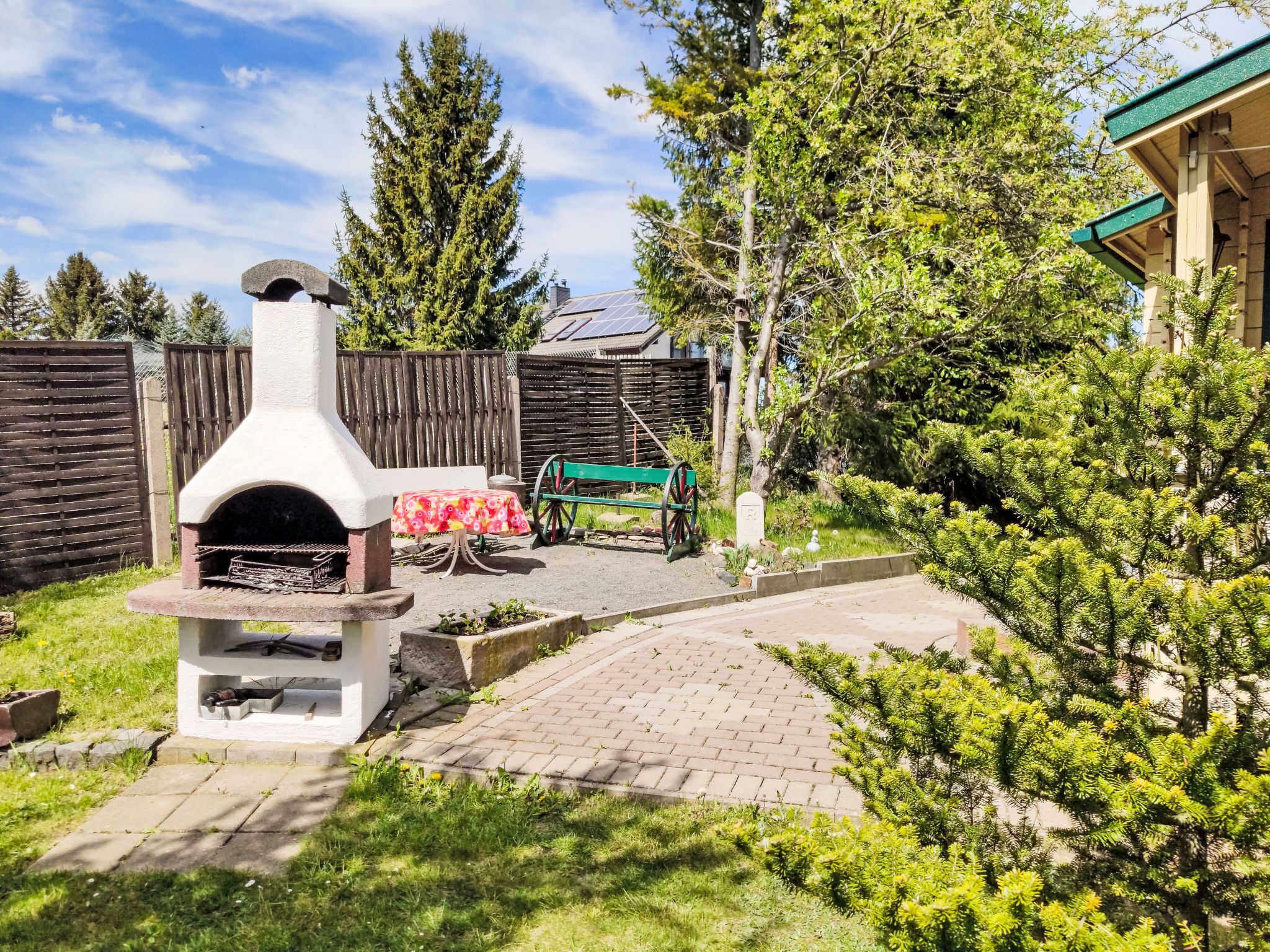 Un jardin avec un four extérieur en pierre, une clôture en bois et un chemin pavé.